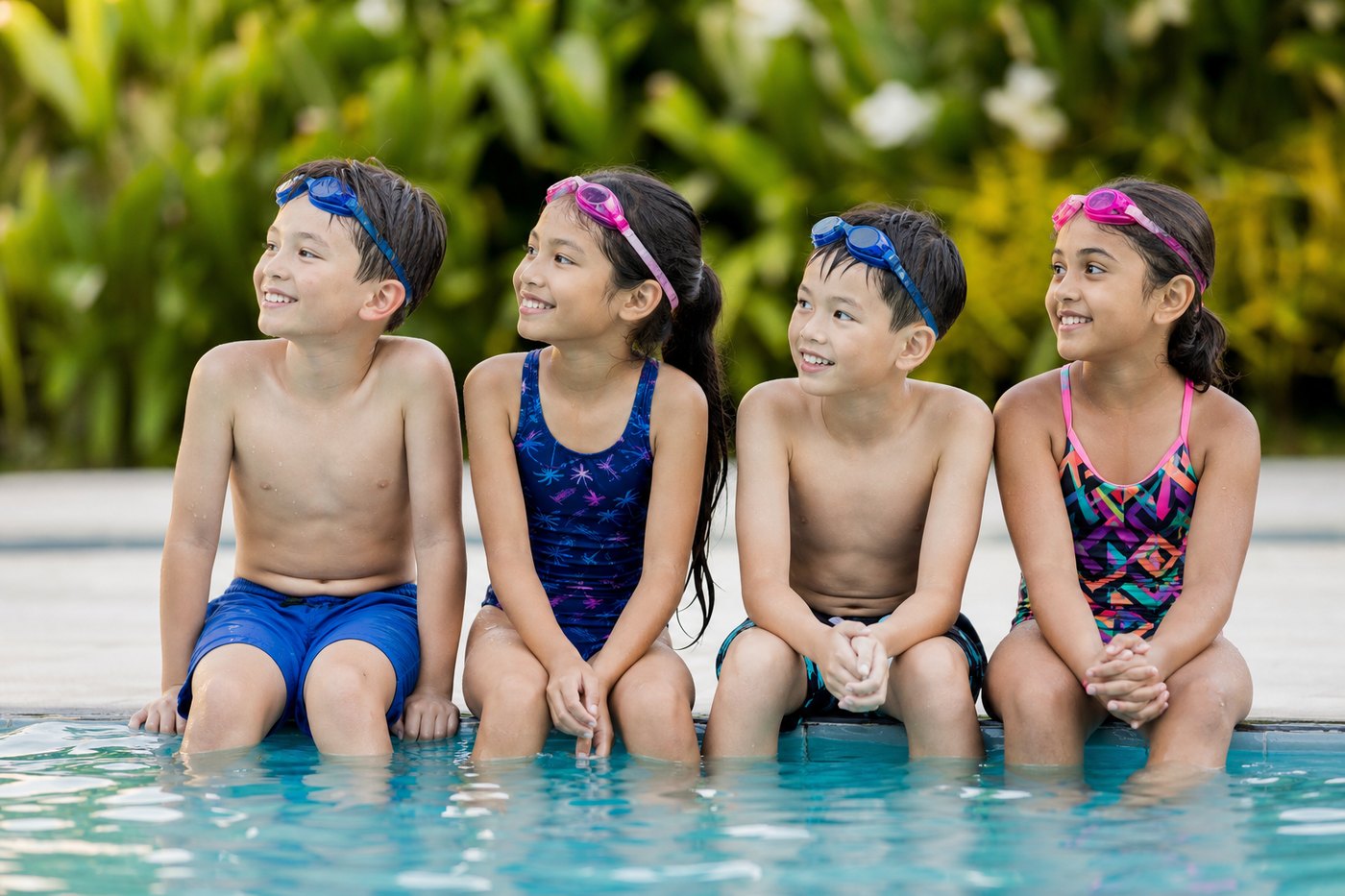 Children sitting on the pool edge listening to their teacher